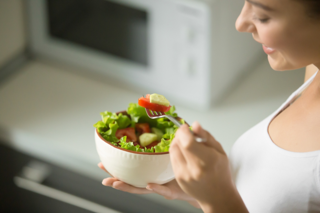 Mulher comendo salada.